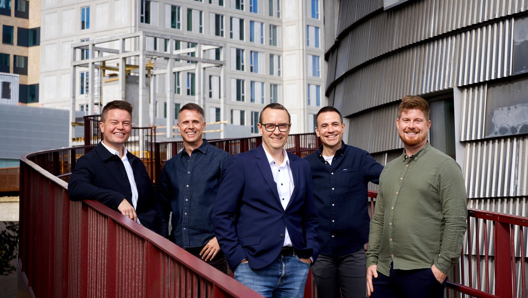 The five employees of Distinkt, standing and seated on a planted terrace.